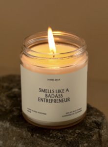 a lit smells like a badass entrepreneur candle on top of a marble counter