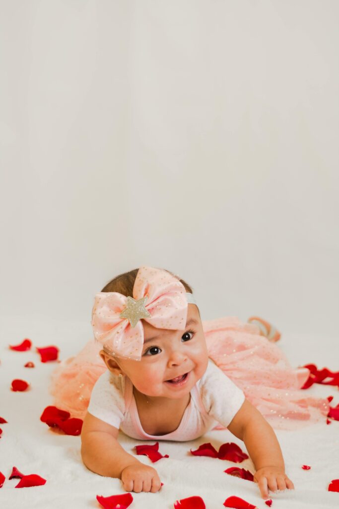 a newborn baby dressed in pink and bows for a photoshoot